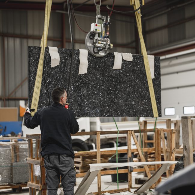 Technicien levant un bloc de granit dans l'atelier